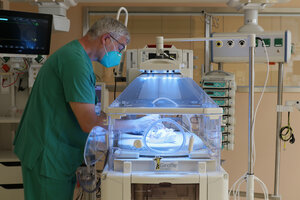 Arzt in grüner Dienstkleidung am Inkubator