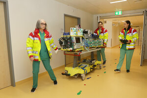 Klinikpersonal mit ECMO-Trage auf Klinikflur