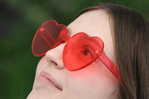 Symbolfoto, junge Frau mit rosaroter Herzchenbrille