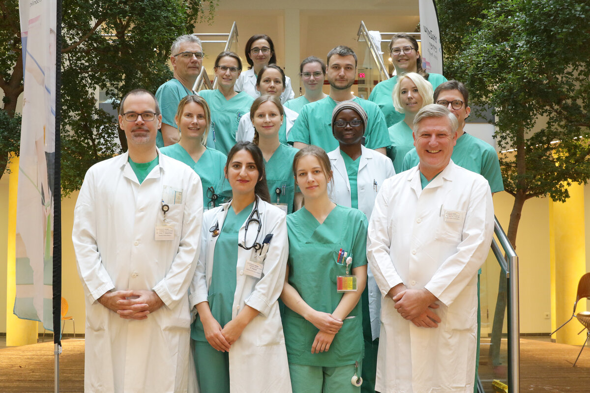 Gruppenfoto vom Team in grüner und weißer Dienstkleidung auf der Treppe im Eingangsbereich des Klinikum Links der Weser