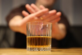 Hände zeigen ein NEIN - im Vordergrund ein Glas Alkohol